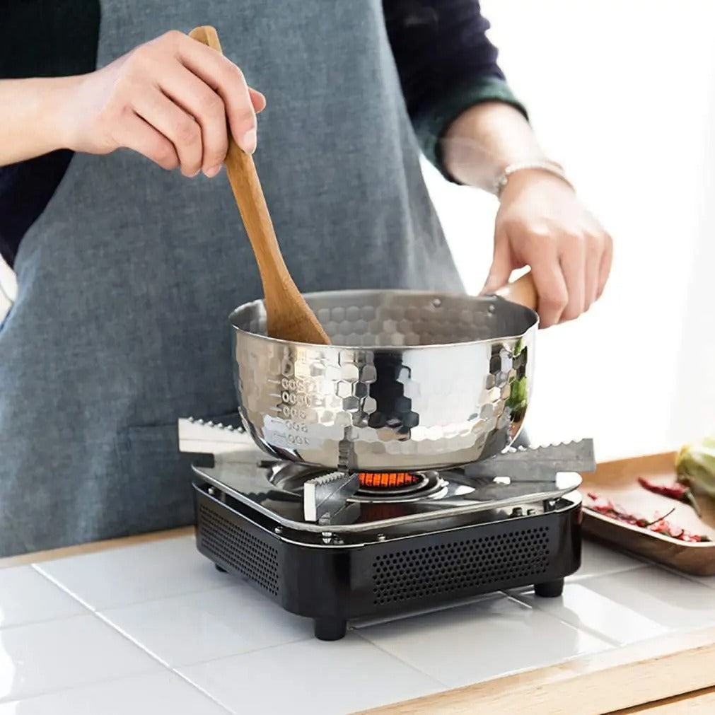 Casserole en Inox Pratique et Durable sur une plaque avec une femme en train de cuisiner dedans