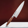 Couteau santoku de chef en acier inoxydable avec poignée originale posé sur une table blanche sur fond marron