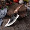Couteau de cuisine viking en acier inoxydable posé sur un morceau de bois avec un tissu et des brindilles à gauche et des légumes au dessus