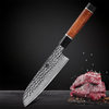 Couteau santoku en acier damassé sur une table grise foncée avec des morceaux de viande crue en bas à droite sur fond gris foncé