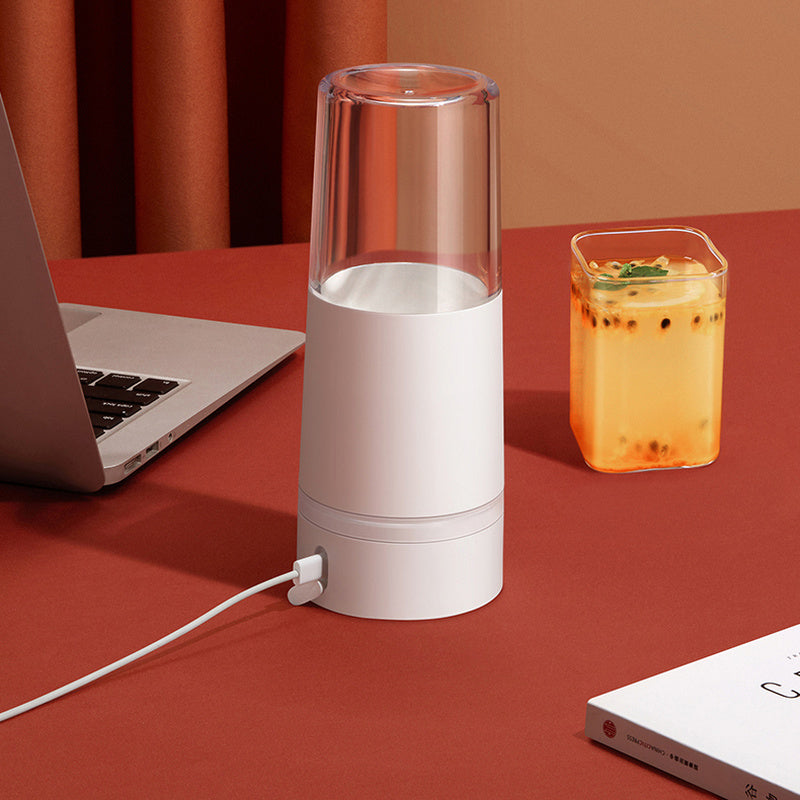 Blender portable original en acier inoxydable rechargeable par mini usb sur une table rouge avec un ordinateur et un verre de jus de fruits sur fond orange